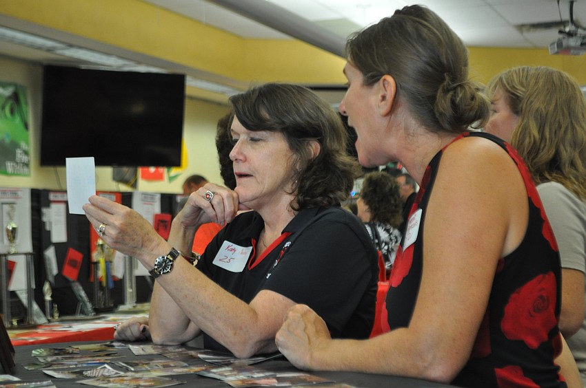 ESE teacher Katy Kimbrell looks through photos with Sonja Vertacnik-Perkins, the sixth-grade science teacher. Both have been at the school more than 20 years.