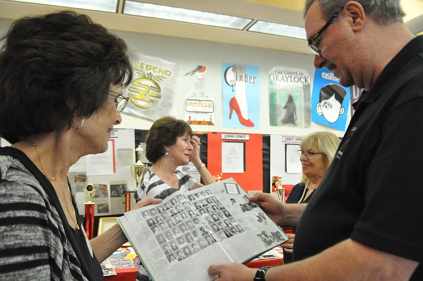 Diann Minero, a former clinic nurse and then school secretary, looks through an old yearbook with Principal Randall Petrilla. 
