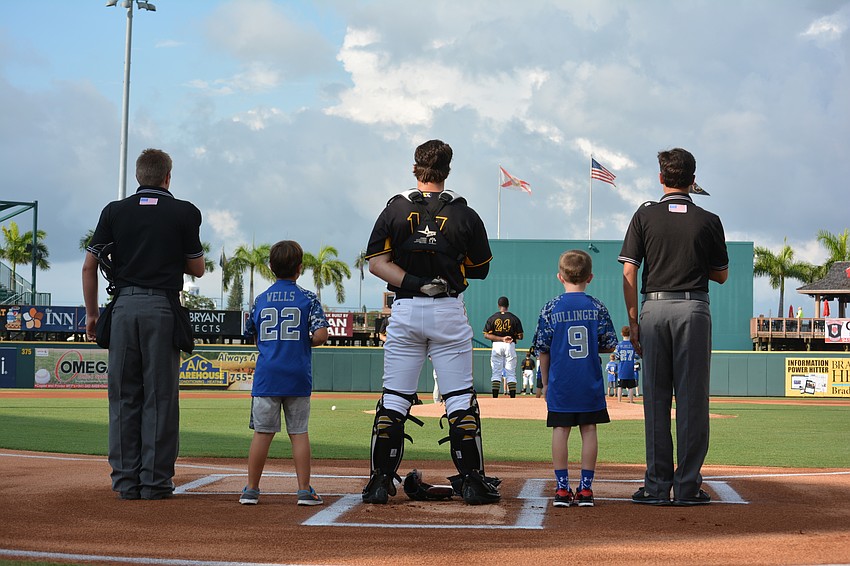 Manatee All-Stars Brady Wells (22) and Parker Hullinger flank Marauder catcher Taylor Gushue at home plate during the playing of the National Anthem.