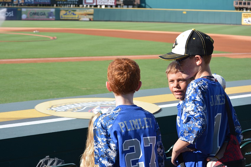 Benjamin Plimley, Benjamin Jameson and Caleb Jameson check out the field from behind the first base dugout.