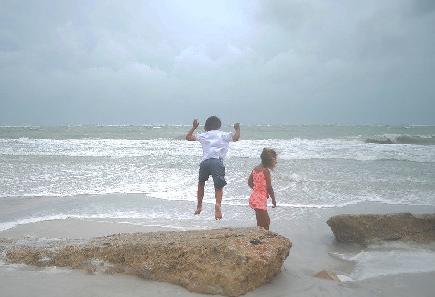 CUTLINE: Carson Aker, 6, jumps off a rock on the beach on Siesta Key Monday, June 6. Carson was on the beach with his mother, Gail Aker, who said she wasn’t worried about the storm, yet.