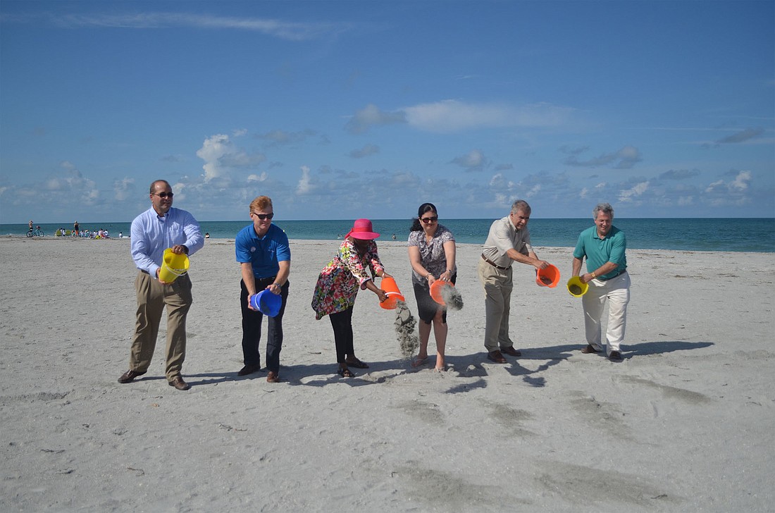 Officials and community members tossed sand on Turtle Beach to commemorate the completion of the county's Siesta Key beach renourishment efforts.