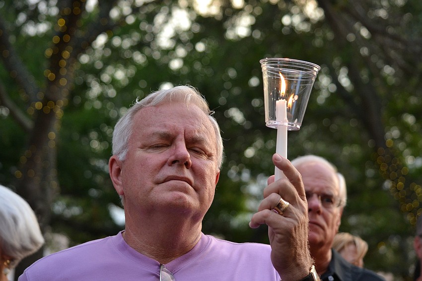 Dennis Stover raises his candle during the vigil.