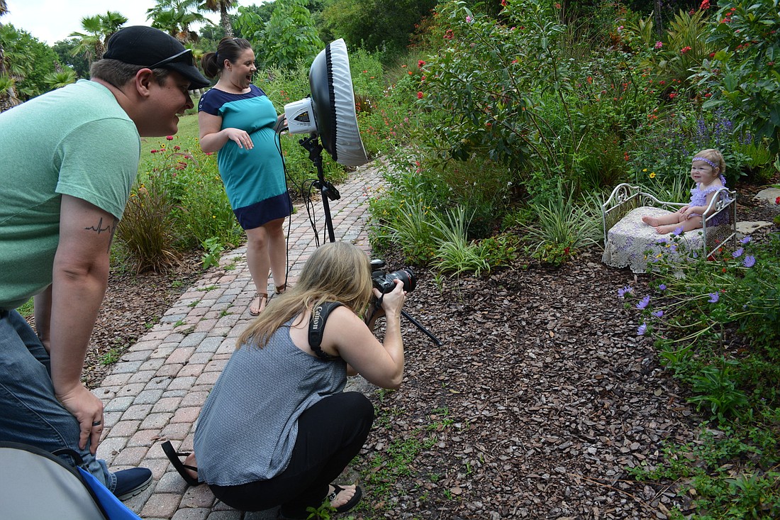 Photographer and nurse Gigi O'Dea photographs Hailey Cassella for her 1-year-old photo shoot, as her parents, Heather and David, watch. O'Dea reserves outside photo sessions for her neighbor's backyard and has brought props, including chicks and rabbits.