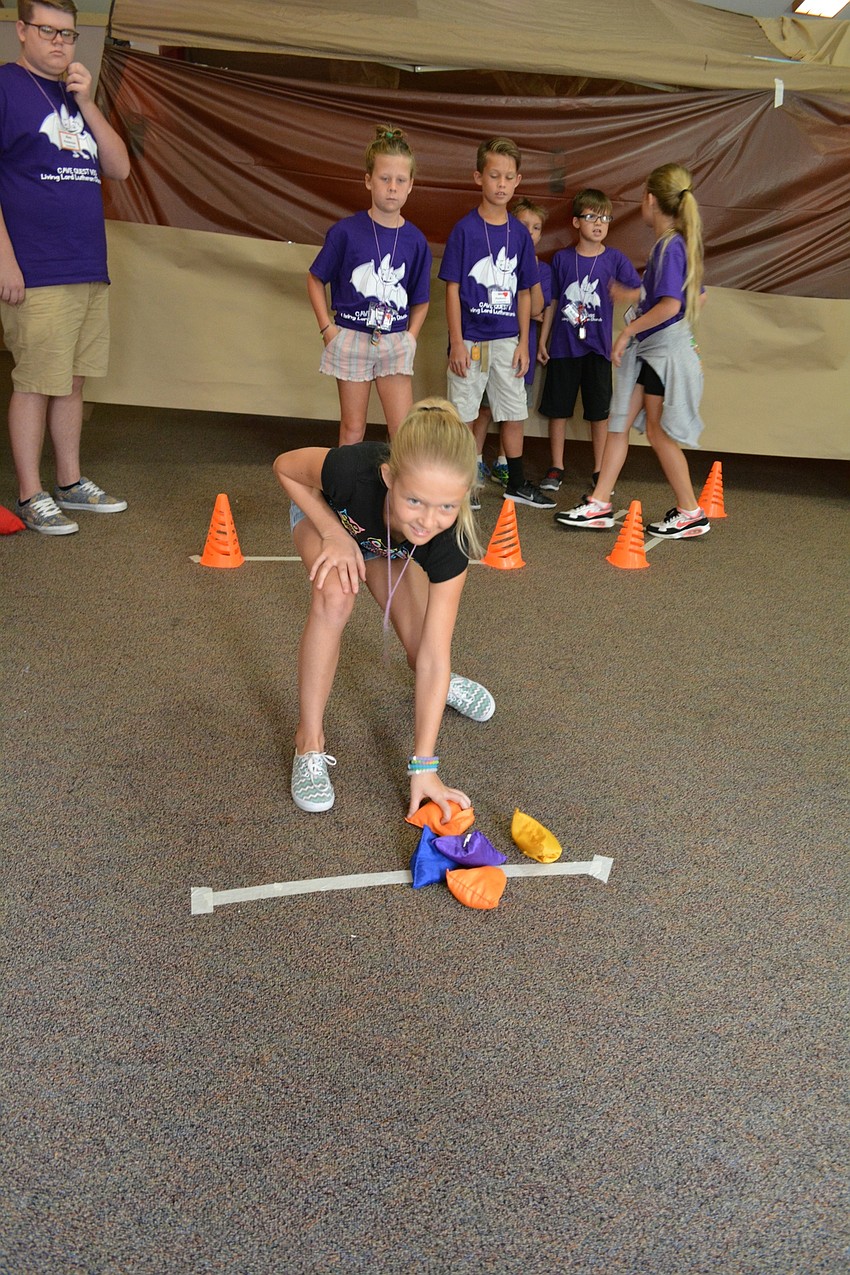 Charlotte West, 10, tries to knock a cone off a stool with a bean bag as part of an indoor obstacle course.