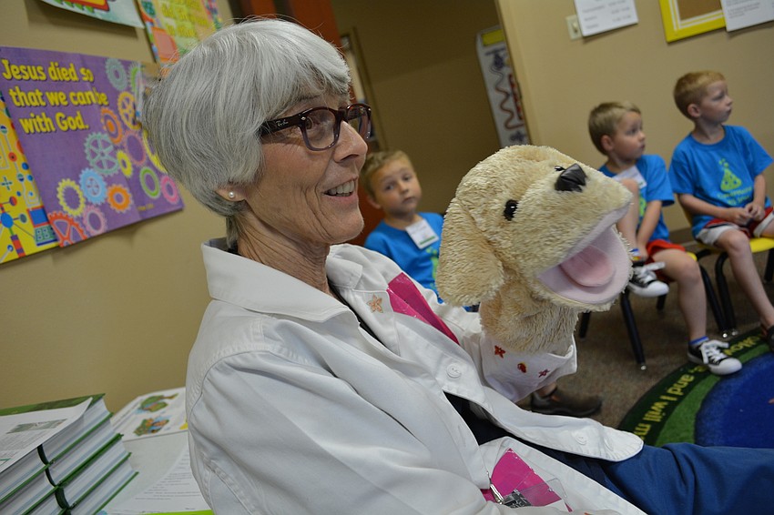 Molly Lisciandro leads children in an activity time, during which they could make cards for children in Cambodia. She uses Sparky, the lab dog, to help give instructions.