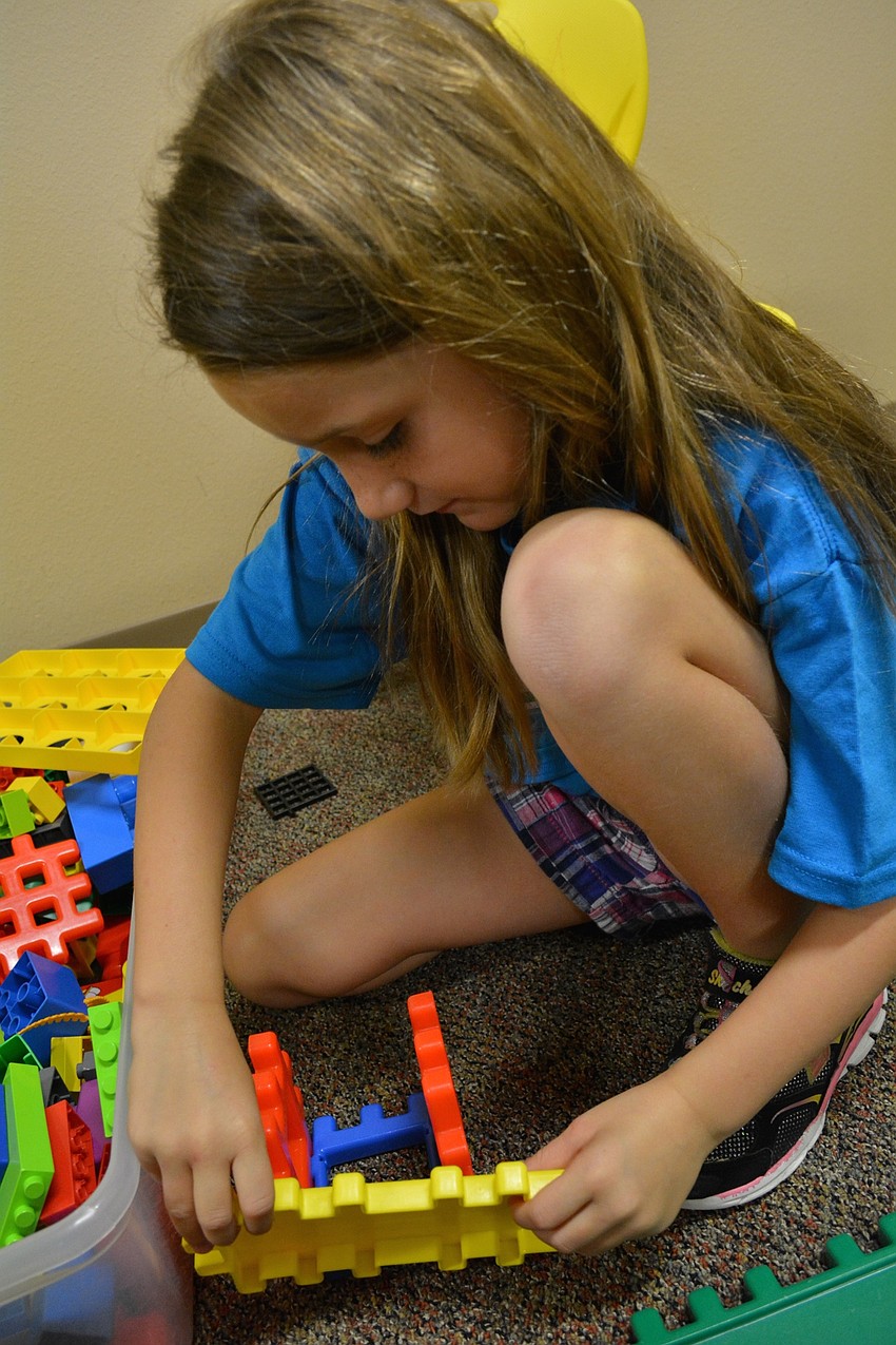 Riley Galasso, 6, builds a house out of blocks.