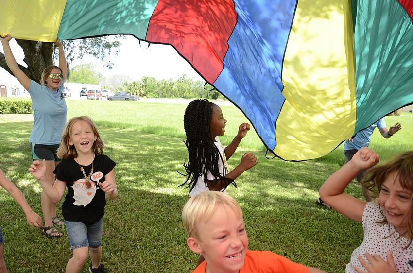 Campers play under the parachute.