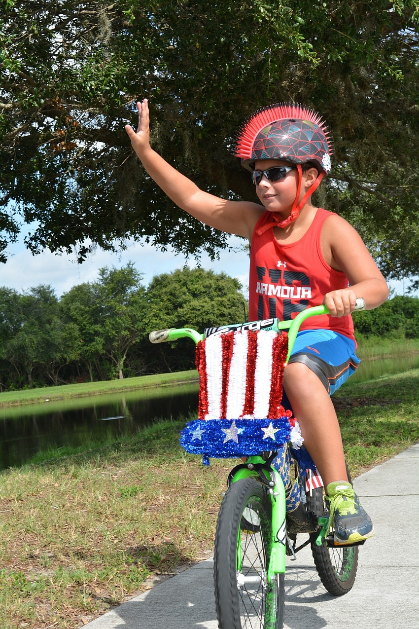 Evan Biermann, 8, waves at friends as he rides in the parade.