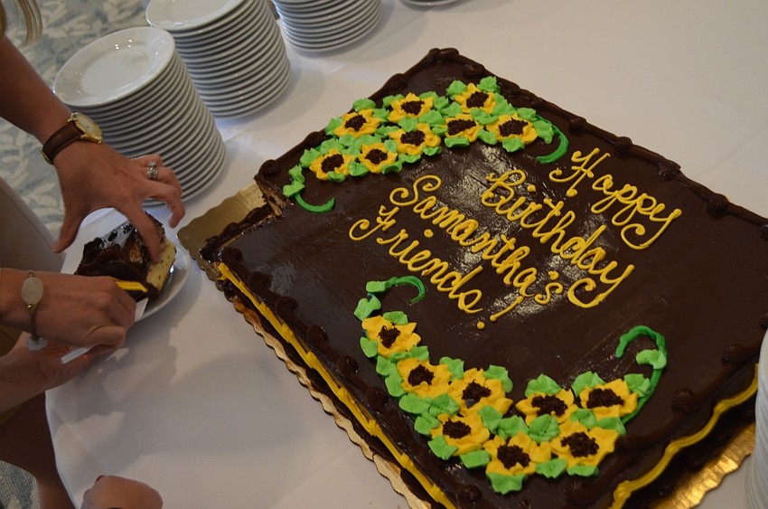 Event staff cutting into the vanilla cake with chocolate frosting.