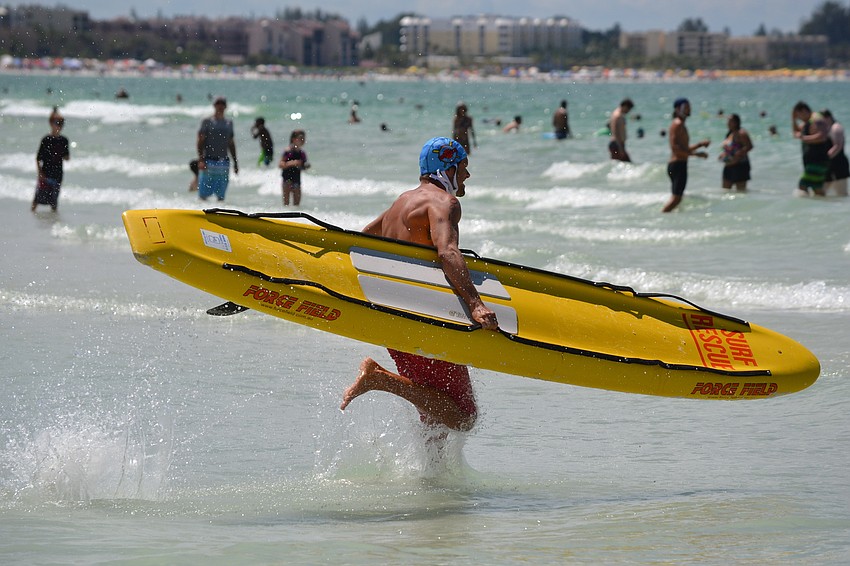 Troy Knopp rushes into the water with his paddle board.