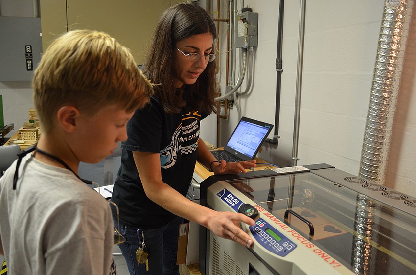 Max Fischer learns how to operate the laser cutter under the supervision of Jennifer Holt.