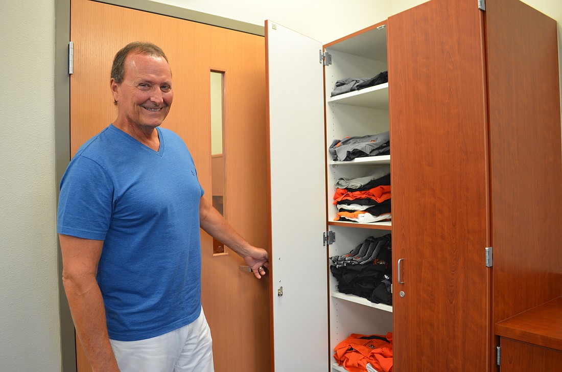 Jeff Hradek opens the cabinet that holds the more than 50 Sarasota High School shirts he's leaving behind for the next principal.