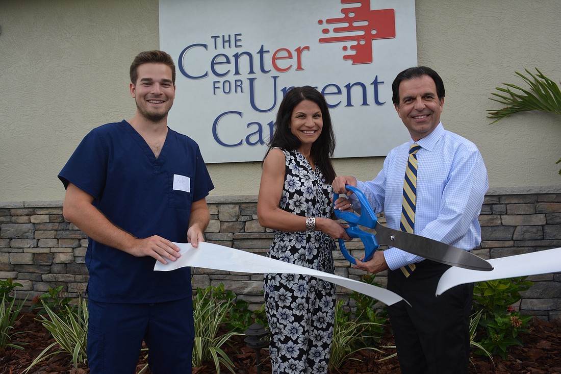 Dr. J. Albert Avila, right, and his wife, Dr. Janet Bailey Avila, cut the ribbon to officially open The Center for Urgent Care. Their son, Kyle Bailey, lends a hand.