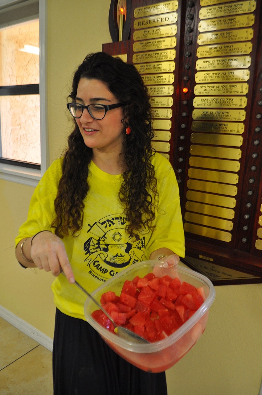 Counselor Chaya Aisenbauch dishes out watermelon, a snack and part of a lesson.