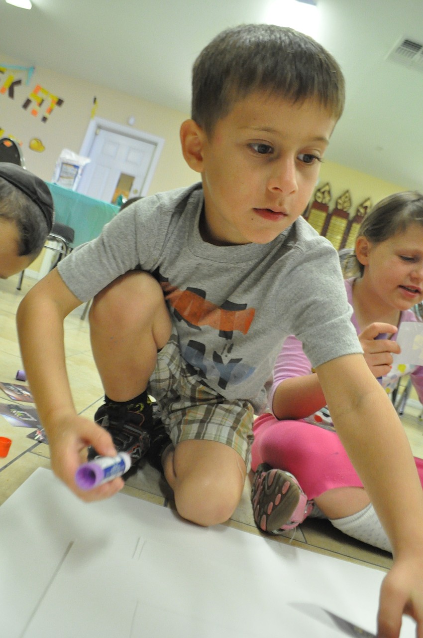 Four-year-old Eitan Neeman glues pictures to a poster board.