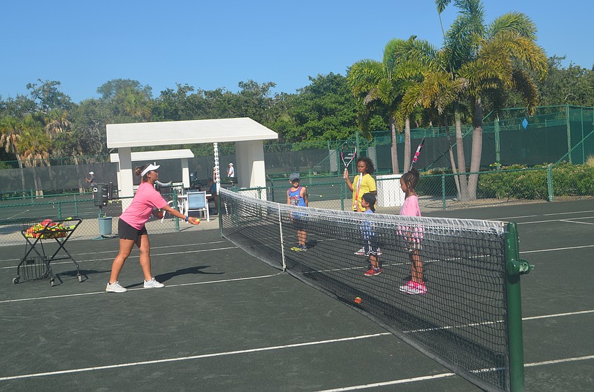 Tennis coach Katelinn Wurm tosses a ball over the net for a warm-up drill.
