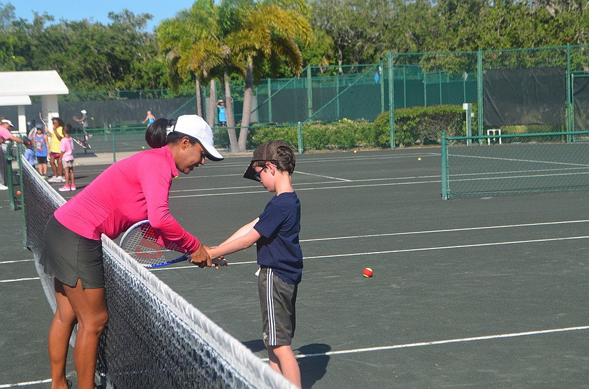 Tennis Camp Director Briana Francois shows Joseph Black, 6, how to hold his racket.