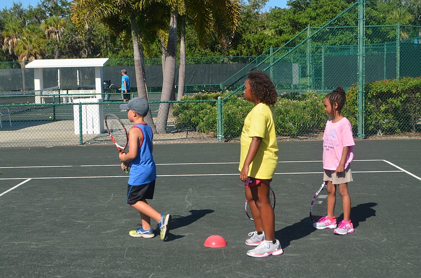 Dylan McLeod, 6, Shama Green, 9, and sister Selina, 6, wait in line during a tennis activity.