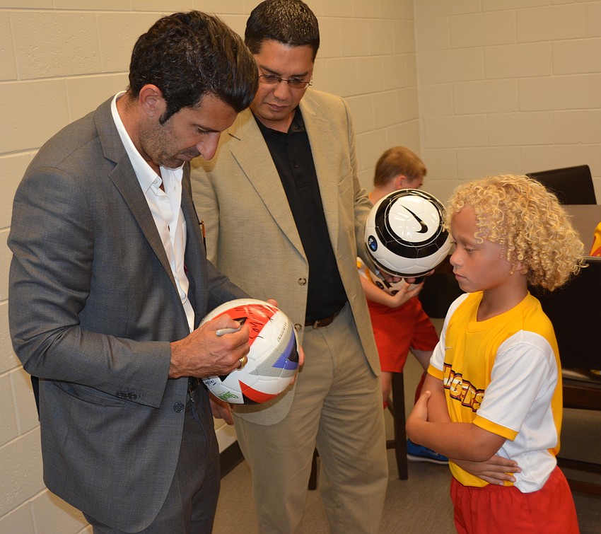 Luis Figo signs a ball for a patient Tayden Burrell, 8, of Panther Ridge.