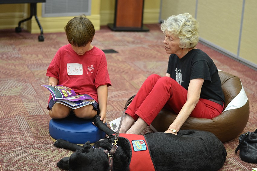 Caleb Sedlak holds Miss Fay's paw while he reads 