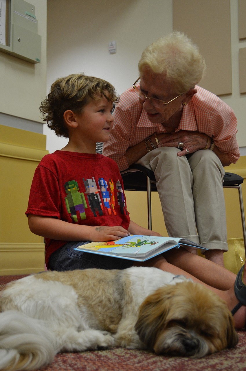 Parker rests his eyes as he is read to by Easton Lopez with assistance by Macie McGee.