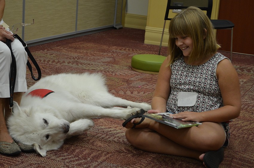 Yukon stretches his paw to Alyssa Murrell as she prepares to read to him.