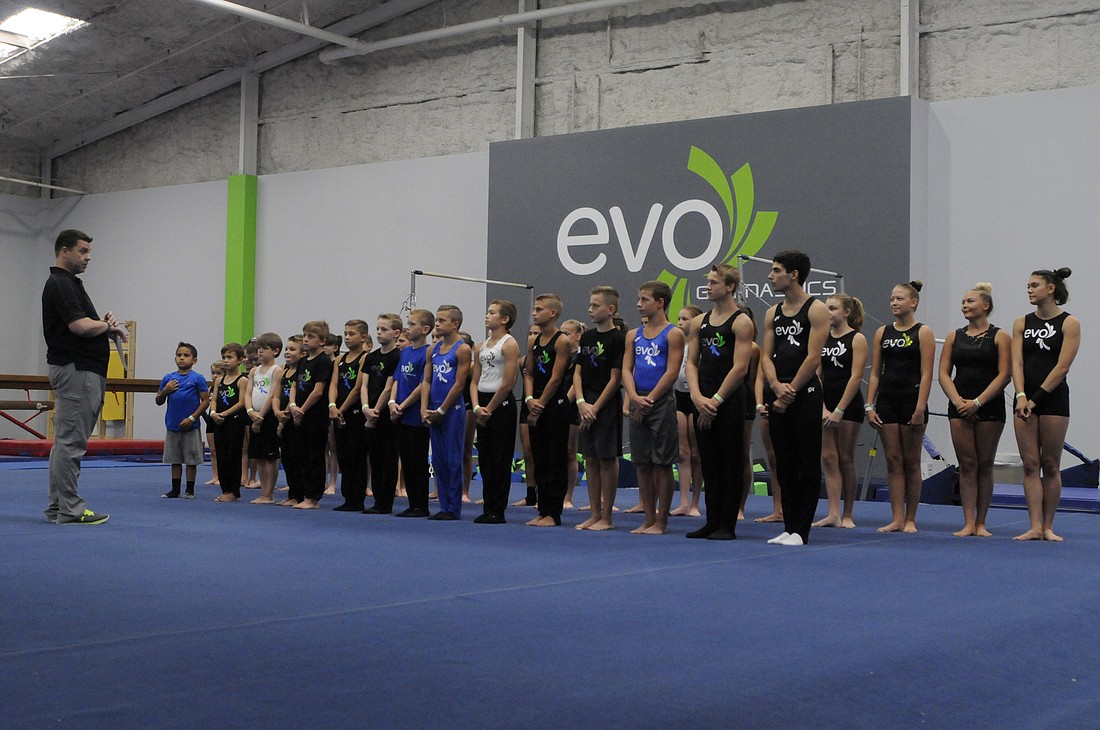 EVO Athletics gymnastics coach Jason Collins works with the team during the gym's grand opening celebration Aug. 6. Photo by Jen Blanco.