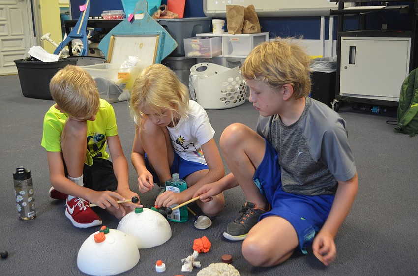 Jace Browne, 7, Marin Walters, 8, and Miles Seafford, 8, pretend to be Mote scientists who are growing coral.