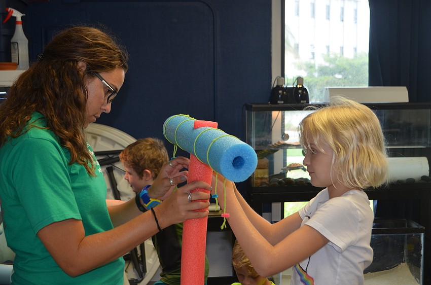 Rainia Lardas and Marin Walters hang staghorn coral from a mock coral tree.