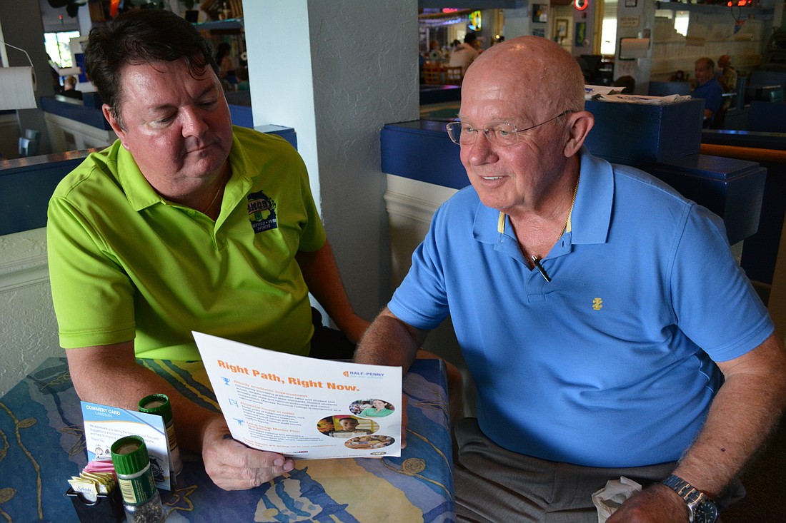 John Horne and Chuck Slater look at promotional material created to promote the school district's portion of the half-cent sales tax.