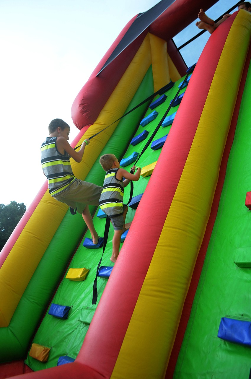 Corey Brown (left), 10,  climbs an inflatable obstacle course with his younger brother, Wyatt Brown, 5, at the first annual Back to School Bash Woodland Community Church Bradenton, Florida on Friday, August 12.