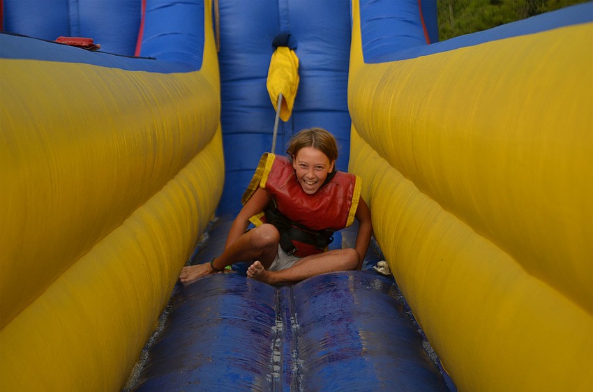 Chloe Brown, 10, of Bradenton, Florida,  laughs as she gets back up after being jerked back by her harness on a bungee-run game at the Back to School Bash at Woodland Community Church.
