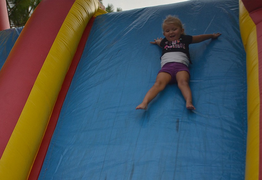 Samantha Encke, 3, of Bradenton, Florida, slides down the inflatable obstacle course at the Back to School Bash at Woodland Community Church. The obstacle course was a hit with the children, who waited in line by the dozens despite the rain.