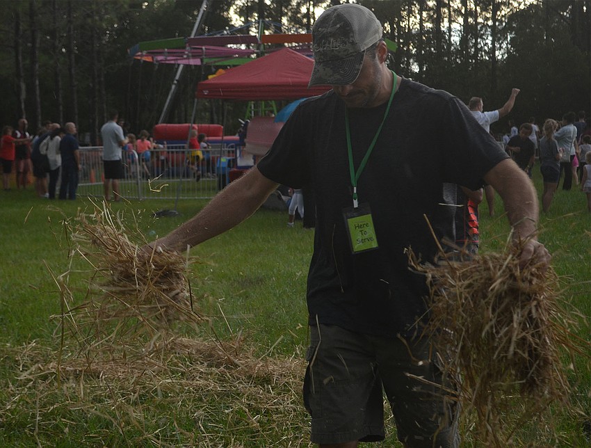 Woodland Community Church Worship Arts Pastor Try Freeman spreads straw on the muddy ground as parents and children wait in line for rides behind him.