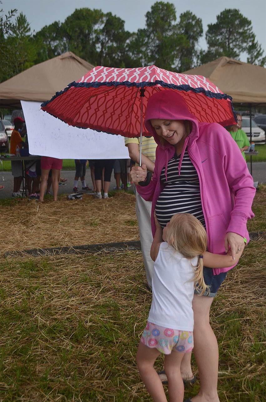 Lucy McCauley, 3, of Sarasota, Florida, huddles underneath her mother's umbrella at Woodland Community Church's Back to School Bash.