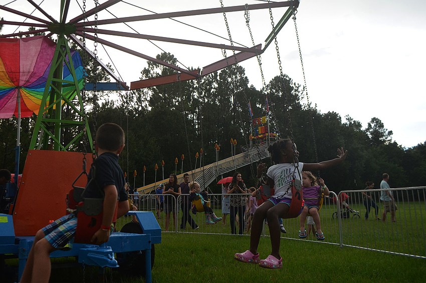 Reina Garnes, 6, waves to her father, Roger Garnes, while she rides the swings at Woodland Community Church's back to School Bash. Reina started first grade last week at Dunn Preparatory School.