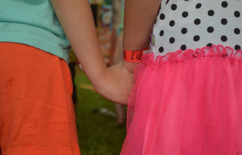 Cassidy Butler, 5, holds hands with, Jocelyn Gomez, 4, while they wait their turn to play on the inflatable obstacle course. The pair only just met during their first week of kindergarten at Dunn Preparatory School.