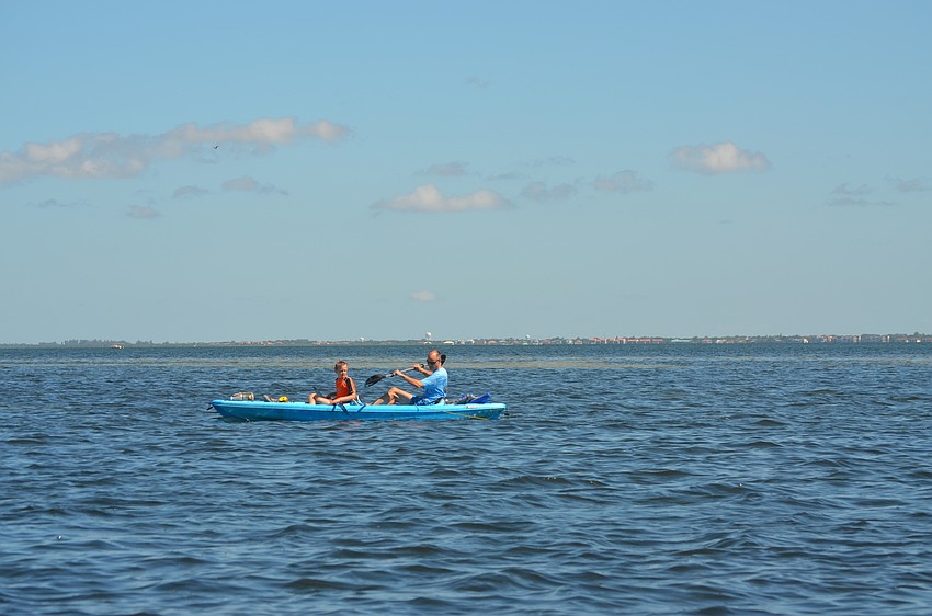 Asher VanDenhoek, 9, and Corey VanDenhoek kayak around the bay during the scallop search.