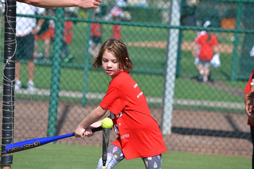Ruby winds up to swing a tennis ball off of the tee.