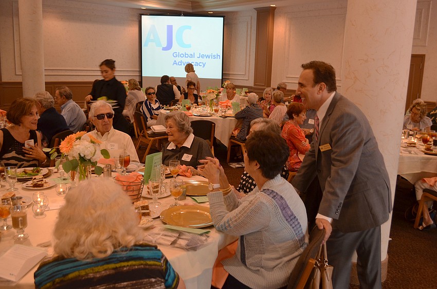 Brian Lipton laughs as he helps a table of attendees determine the winner of the floral centerpiece. Lipton decided that the attendee with the most A’s, J’s and C’s in their name would be the winner at each table.