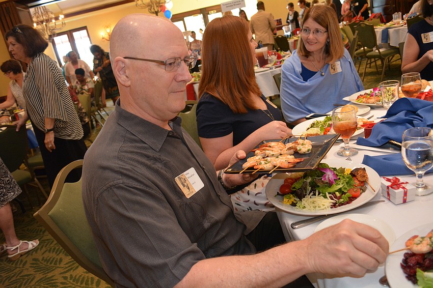 Mike Monahan, of Sarasota, passes toppings for the salad.