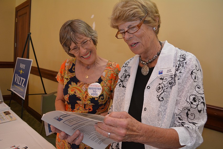 Volunteers Becky Clapp and Judy Achre flip through the voters guides they distribute to guests visiting the booth of the League of Women Voters of Sarasota County.