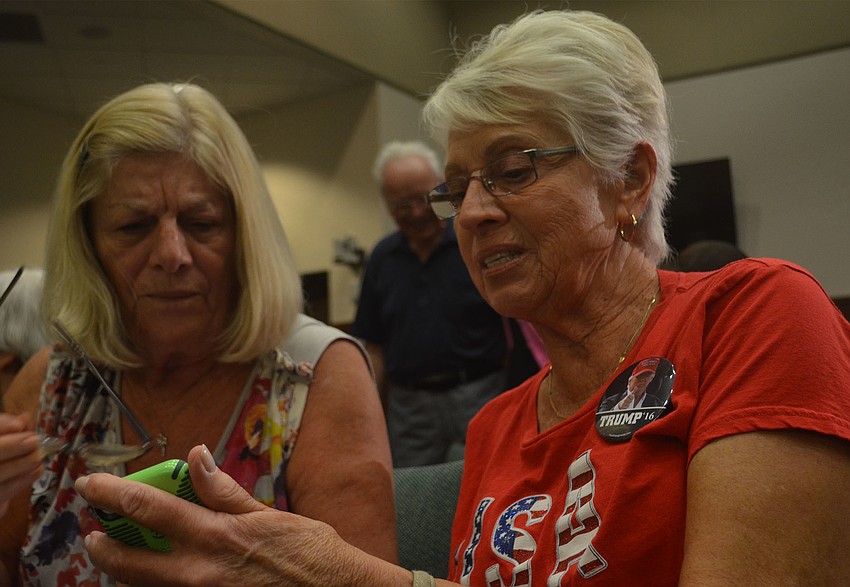 Irene Popyk (left) and Joan Combes (right) search for Republican candidate for the House of Representatives Joe Gruters campaign information between panels.