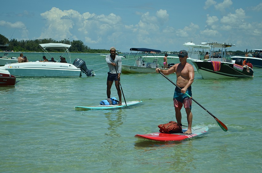 Devon Walcott and Rob Alfieri paddle up to Party on the Pass Sunday afternoon.
