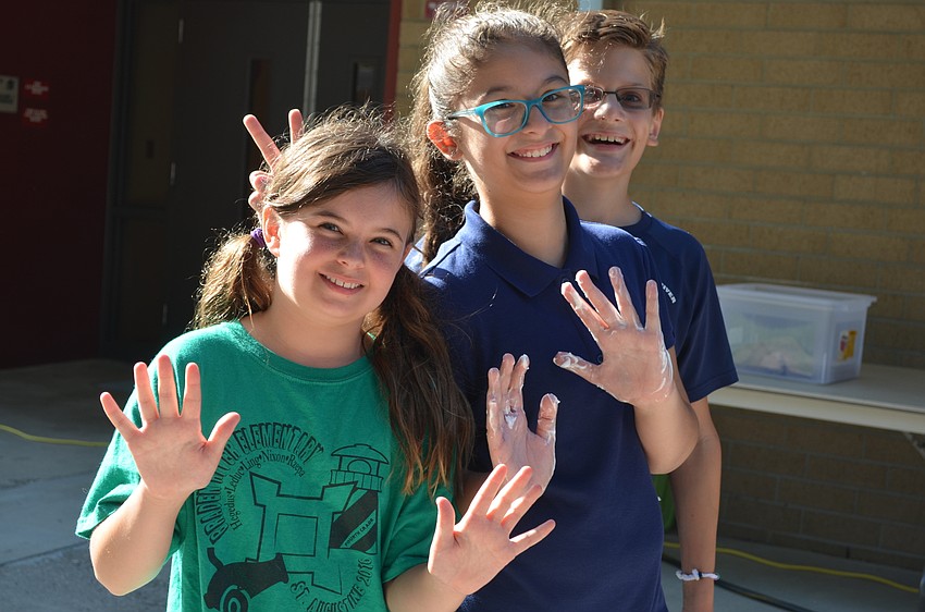 Kayla Foroughi and Megan Bovaird show their shaving cream-covered hands.