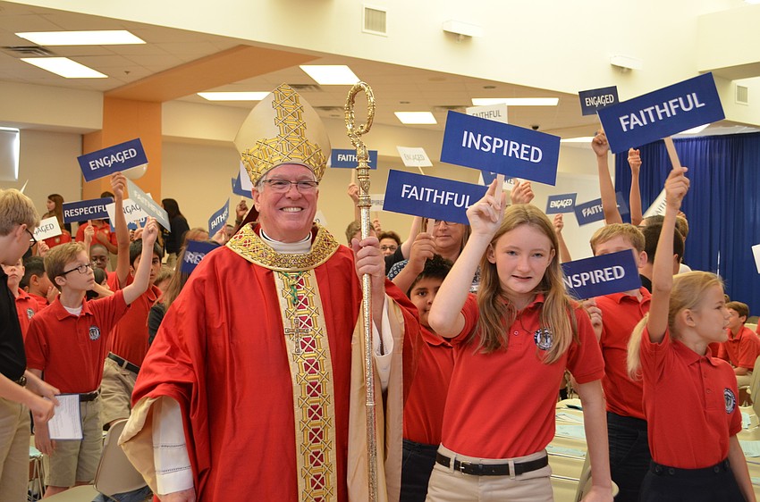 Bishop Frank Dewane stands with Students stand with words used to spell out the St. Mary motto of F.I.R.E