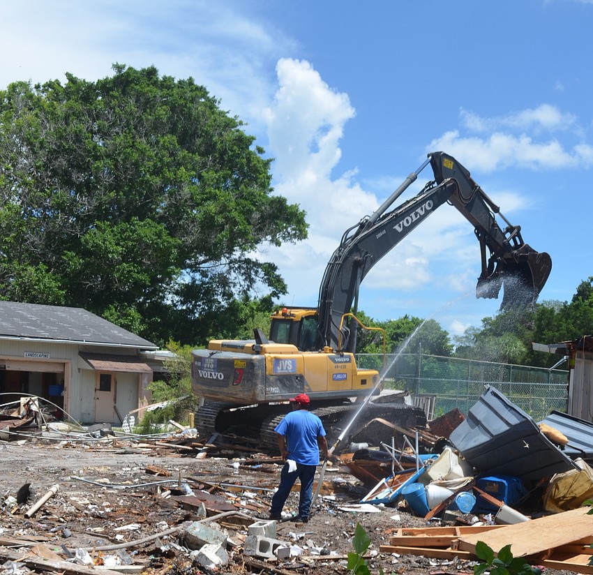 A worker hoses down the metal teeth of an excavator as it demolishes a service building on the Colony Resort grounds on Longboat Key.