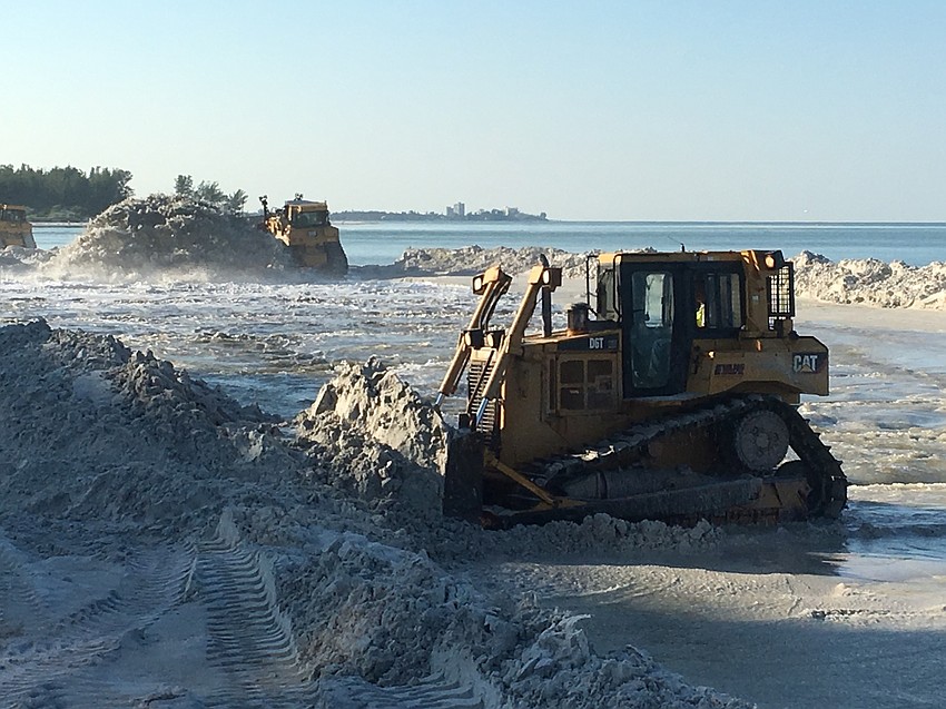 Bulldozers shape the sand being pumped form New Pass onto Longboat Key.