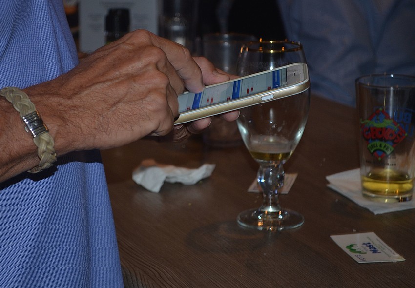 Richard Dorfman monitors polling results on his phone at Teresa Mast's campaign watch party. Many partygoers closely watched their phones as precincts continued to release results showing Zucker maintaining an early lead.